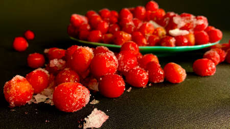Cold cherry in the winter season. Many ripe red cherries in ice are scattered on the table