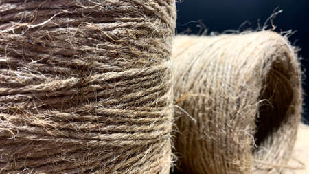 Large puffs of brown jute. Special beige rope wound in rolls on a black background