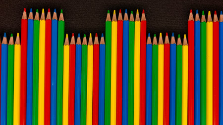 Bright multi-colored pencils for drawing lies on a black tableの写真素材