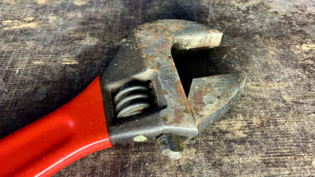 An old adjustable wrench with a red handle lies on the workshop tableの写真素材