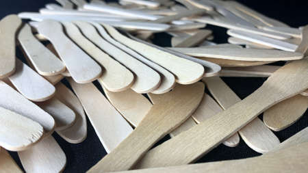 Different shaped wooden ice cream sticks are scattered on a black table