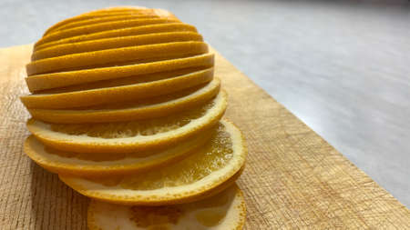 A ripe orange cut into slices lies on the tableの写真素材