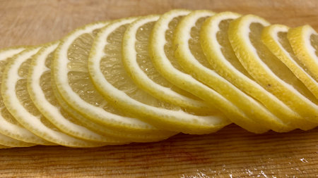 A ripe orange cut into slices lies on the tableの写真素材