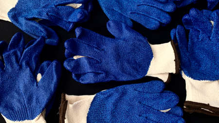 Technical gloves for construction with a blue anti-slip coating on the inside of the hand on a black...