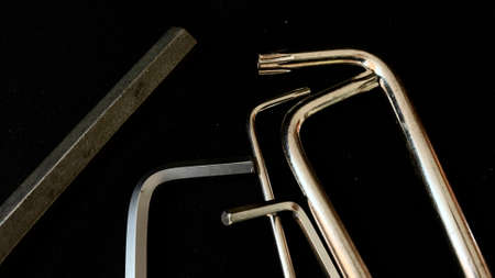 Chrome tools hex wrench for construction work with medel and machines lie on a black background
