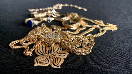 Jewelry made of high quality real gold with precious stones and sparkles lies on a black table. Rings, earrings and necklaces emphasizing feminine beautyの写真素材