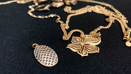 Jewelry made of high quality real gold with precious stones and sparkles lies on a black table....