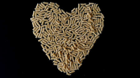 A whole package of pasta from durum flour scattered lies on the black table of the cook and is ready...