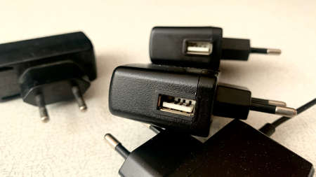 Different types of chargers for electrical devices, black wires, connectors and battery packs lie on...