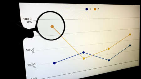 An office worker shows his colleagues a presentation with a company development graph at night on the company's computerの写真素材