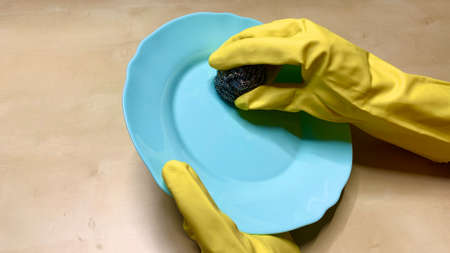 Woman in rubber cleaning gloves prepares to clean up her house using sponges, rags and cleaning productsの写真素材