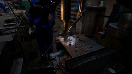 An industrial plant where an employee works on a metal drilling machine