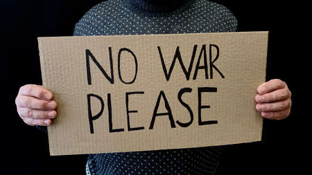 Man holds a cardboard sign in his hands asking for the abolition of the war. world peace. Protests...