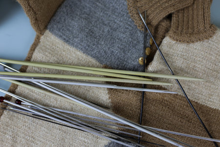 Knitted clothes with knitting needles, wool and threads with metal knitting needles, background with...