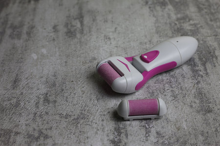 Electric callus remover. Sanding roller for removing rough skin from the feet. Pink grinding head on electric tool for skin careの写真素材
