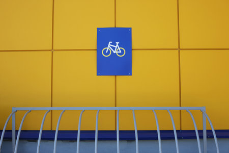 Yellow wall with bicycle parking sign and a metal structure for closing the lock on the bike to guard it in front of the shopping centerの写真素材
