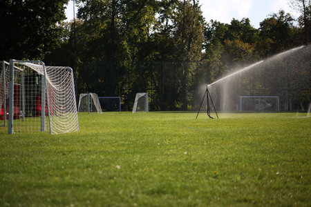 Lawn watering system for playing football. Spraying water on a grassy field for playing a sports gameの写真素材