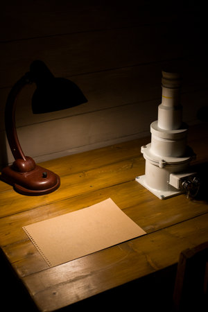Vintage table with old paper illuminated by a warm lamp next to a scintillation counter at a work...