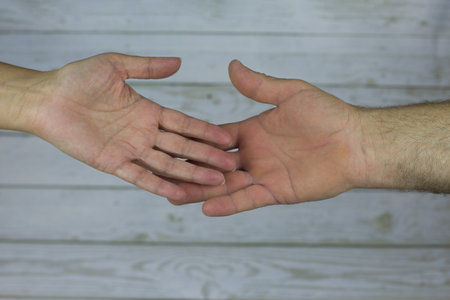 Older female and male hand reach out to each other with open palms turned towards the camera....