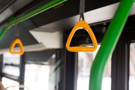 Yellow holder in the bus on the handrail under the ceiling in the shape of a triangle for easy grip by hand. Taking care of passengers in modern urban vehiclesの写真素材