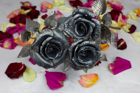 Bouquet of metal roses for the holiday on background of rose petalsの写真素材