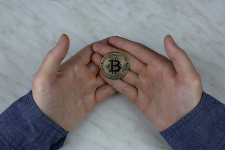 Bitcoin in the hands of man, cryptocurrency coin physical version with a built-in chip with money, expensive coin for investmentの写真素材