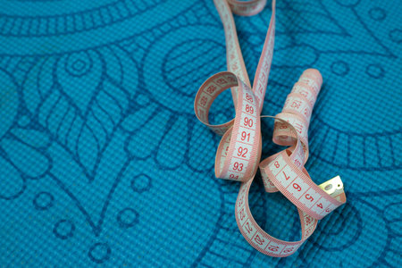 Flexible plastic body measuring tape lies on sports mat, sports and healthy lifestyle concept with...