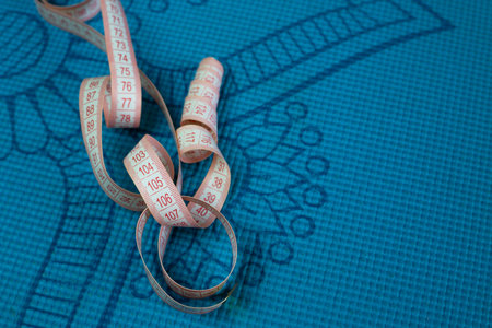 Unraveled flexible body measurement tape lies on sports mat for doing sports, sport and healthy...