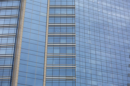 Glass facade of skyscraper with office space. Modern blue glass building, exterior feature of multi...