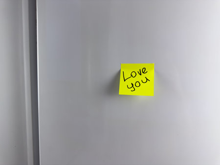 Love you. The inscription on sticky note hangs on the refrigerator. Second half left romantic message to them loved one before leaving for work. Cute sticker with words of love on refrigeratorの写真素材
