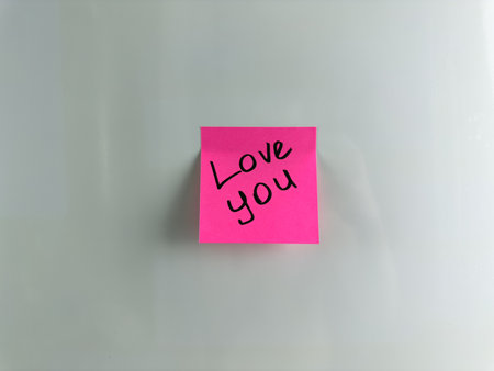 Pink sticky note written with marker - Love you. Important words in romantic message left on the refrigerator. Please your soulmate with a simple reminder of your feelingsの写真素材