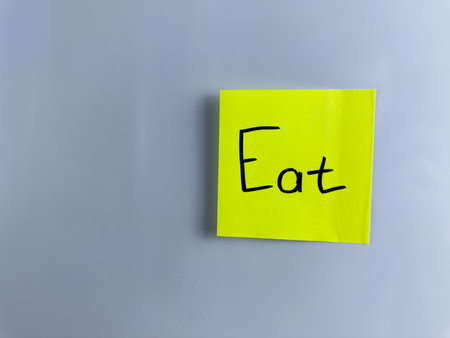 The inscription eat on colored sticky note. Note with the word Eat for nutrition project. Simple conceptual photo about the main human need for proper nutrition for healthの写真素材