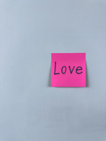 Sticky note with Love written on it, set on a white background. Image symbolizes love, care, and closeness, ideal for personal and romantic themes. Perfect for concept illustrationsの写真素材