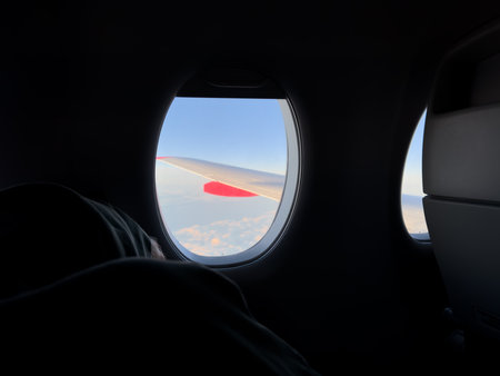 Peaceful moment inside airplane cabin with sleeping passenger near window, soft light illuminating...