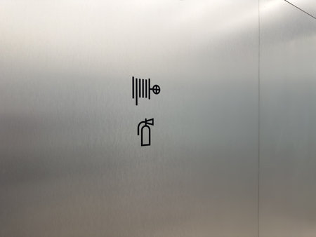 Wall mounted fire safety sign showing fire hose and extinguisher icon. Clean metal background...