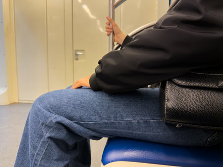 Passenger sitting comfortably in metro train holding onto handrail. Highlighting daily commute,...