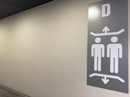 Simple elevator direction sign with minimalistic male figures and arrows on a gray wall in modern interior, concept of navigation and public transport infrastructureの写真素材