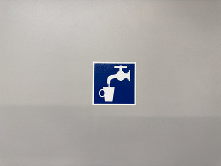 Blue and white symbol of a water tap pouring into a cup, indicating access to drinkable water in a public place, concept of hydration, health, and clean infrastructureの写真素材