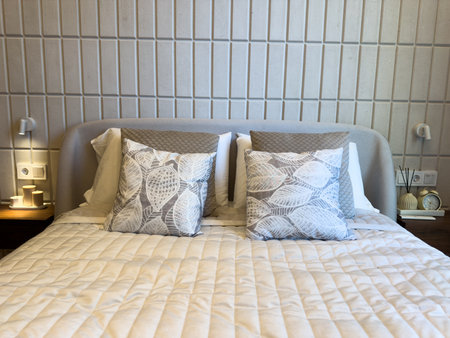 Cozy bedroom featuring soft bed with textured blankets, two decorative pillows with leaf patterns,...