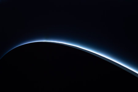 Abstract background with a glowing blue curve on dark surface. Minimal futuristic gradient design ideal for creative projects, digital presentations, websites, and advertisingの写真素材