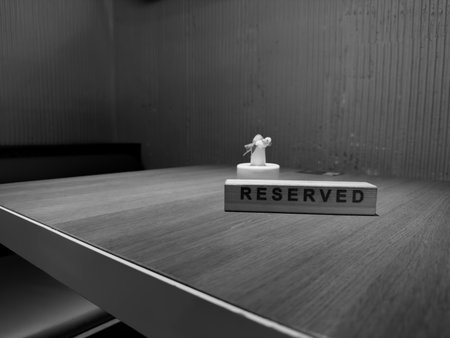 Black and white photo of reserved sign on wooden table, conveying a sense of quiet elegance and calm. Minimalist design and soft lighting evoke feelings of exclusivity and peaceの写真素材