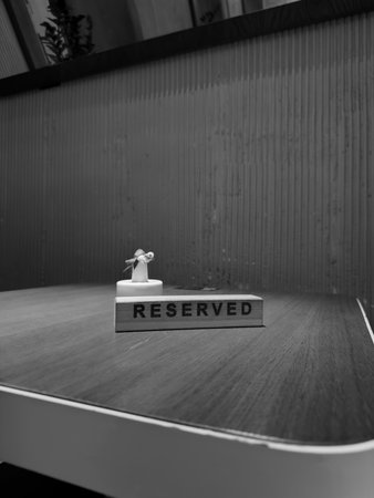 Black and white image of reserved sign on empty table, evoking feelings of loneliness, waiting, and longing. Symbol of unfulfilled expectations in quiet, solitary settingの写真素材