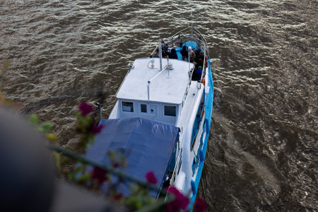 Boat passengers carrying on water, seen from above. The scene captures peaceful moment of travel,...