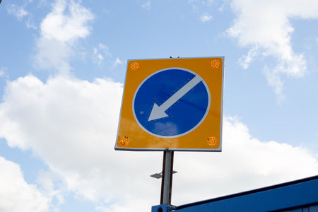 Road sign with blue circle and downward arrow, enhanced by glowing orange dots at each corner for increased visibility, ensuring safe and clear traffic direction even in low light conditionsの写真素材