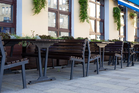 Modern outdoor seating arrangement with benches and tables, accented by decorative planters. The minimalist design creates an inviting space for social gatherings in urban environmentsの写真素材