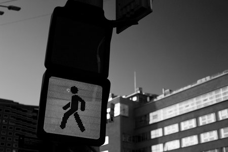 Black and white image of pedestrian signal depicting walking figure, need for caution in urban environments. Hidden dangers of traffic and significance of personal responsibility in road safetyの写真素材