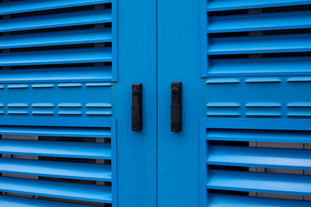 Close up shot of blue metallic door with ventilated slats, designed for industrial or commercial...