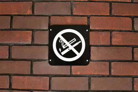 No smoking and no vaping sign displayed on brick wall, highlighting prohibition of both traditional cigarettes and electronic cigarettes and vapes in public spaces, emphasizing health concernsの写真素材