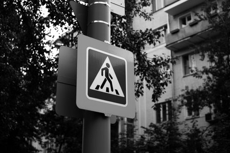 Black and white image of pedestrian crossing sign, symbolizing road danger, accidents and the...