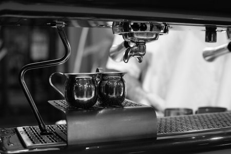Close up shot of barista brewing espresso using professional coffee machine. Shiny metal jugs and...